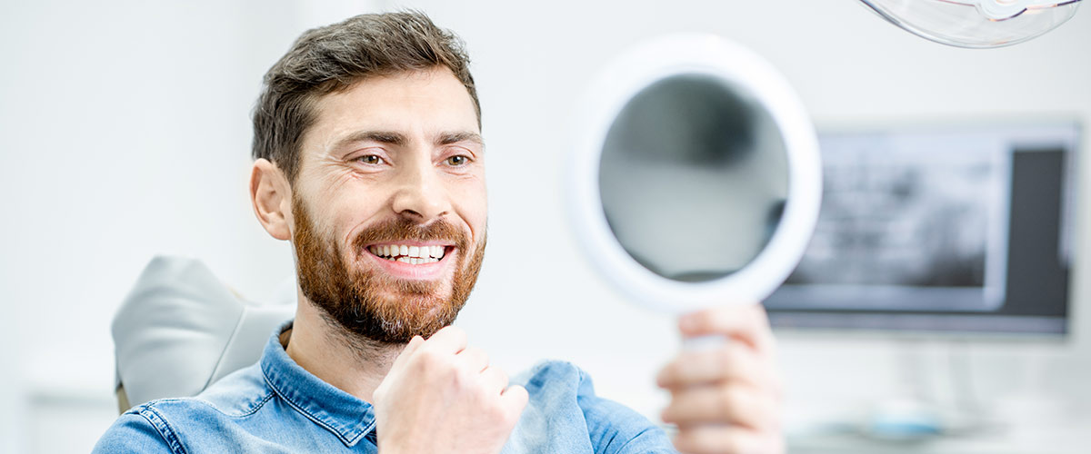 smiling person looking in hand mirror