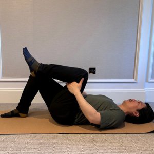 laying on the ground pulling leg towards body