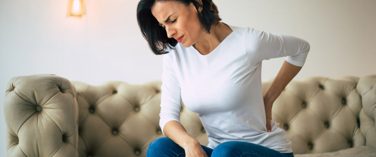woman sitting on couch with sciatica pain