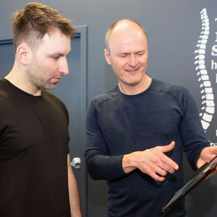 Dr. Tim showing a model of a spine to a patient.