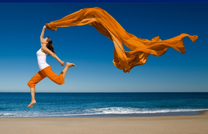 A woman on the beach jumping in the air