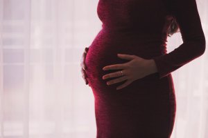 Silhouette of a pregnant woman gently holding her belly, emphasizing motherhood and anticipation.
