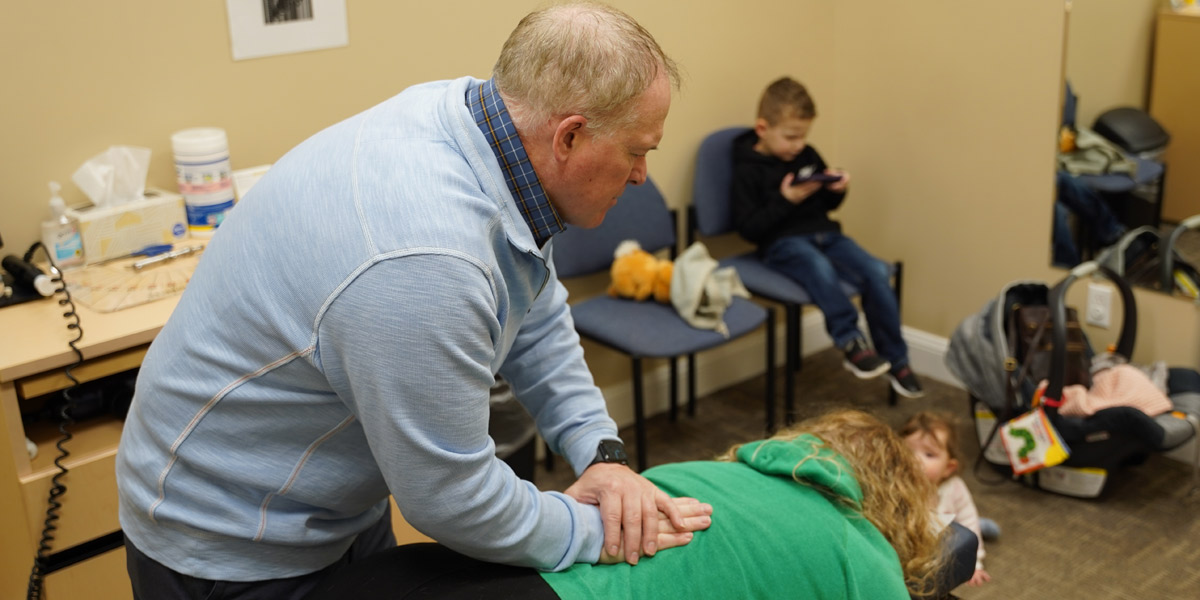 Dr. Brad Double adjusting a mother with her children in the room