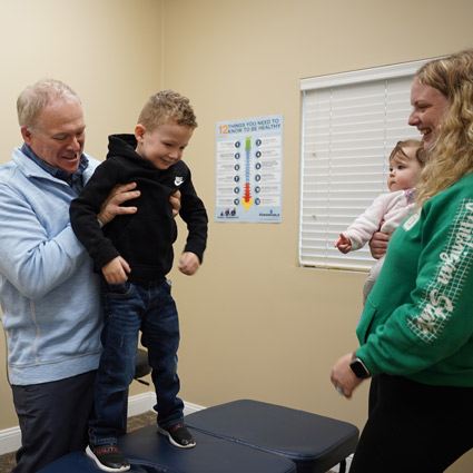 Dr. Brad Double lifting a child onto the adjustment table