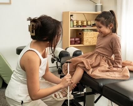 Inglewood chiropractor checking paediatric patient's reflexes