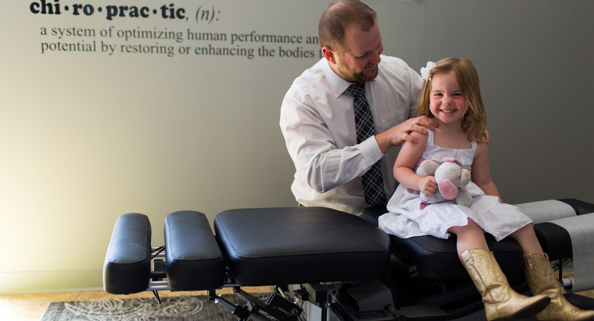 Dr. Nicholas Damato adjusting a girl who is smiling