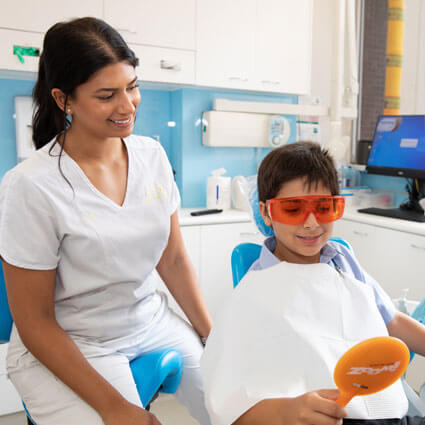 child in dental chair looking in mirror