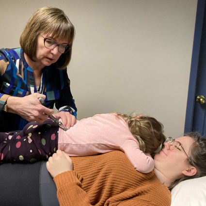 Child being adjusted while lying on her mom