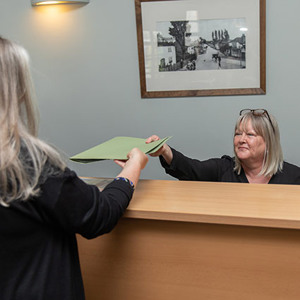 handing patient paperwork at front desk