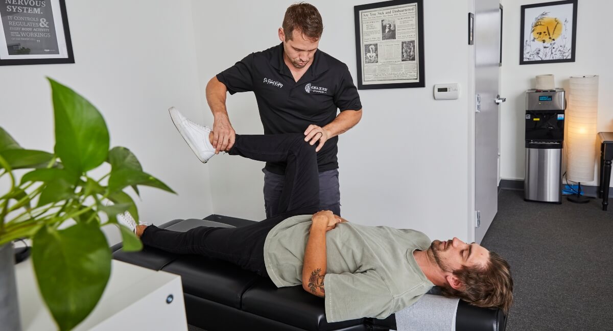 Dr. Robert of Awaken Chiropractic Center adjusting adjusting patient's legs