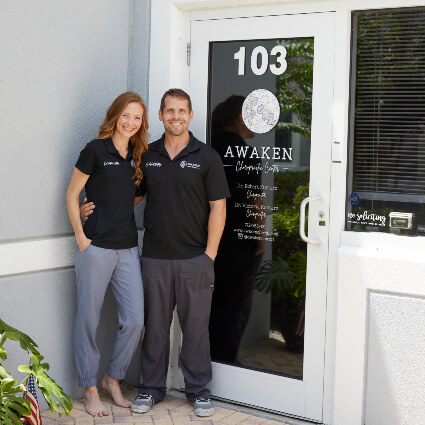 Port St Lucie chiropractors Dr. Victoria and Dr. Robert standing at practice entrance