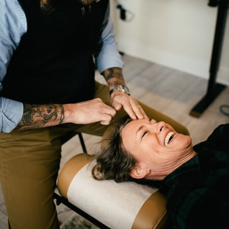 Smiling female patient receiving adjustment from a chiropractor