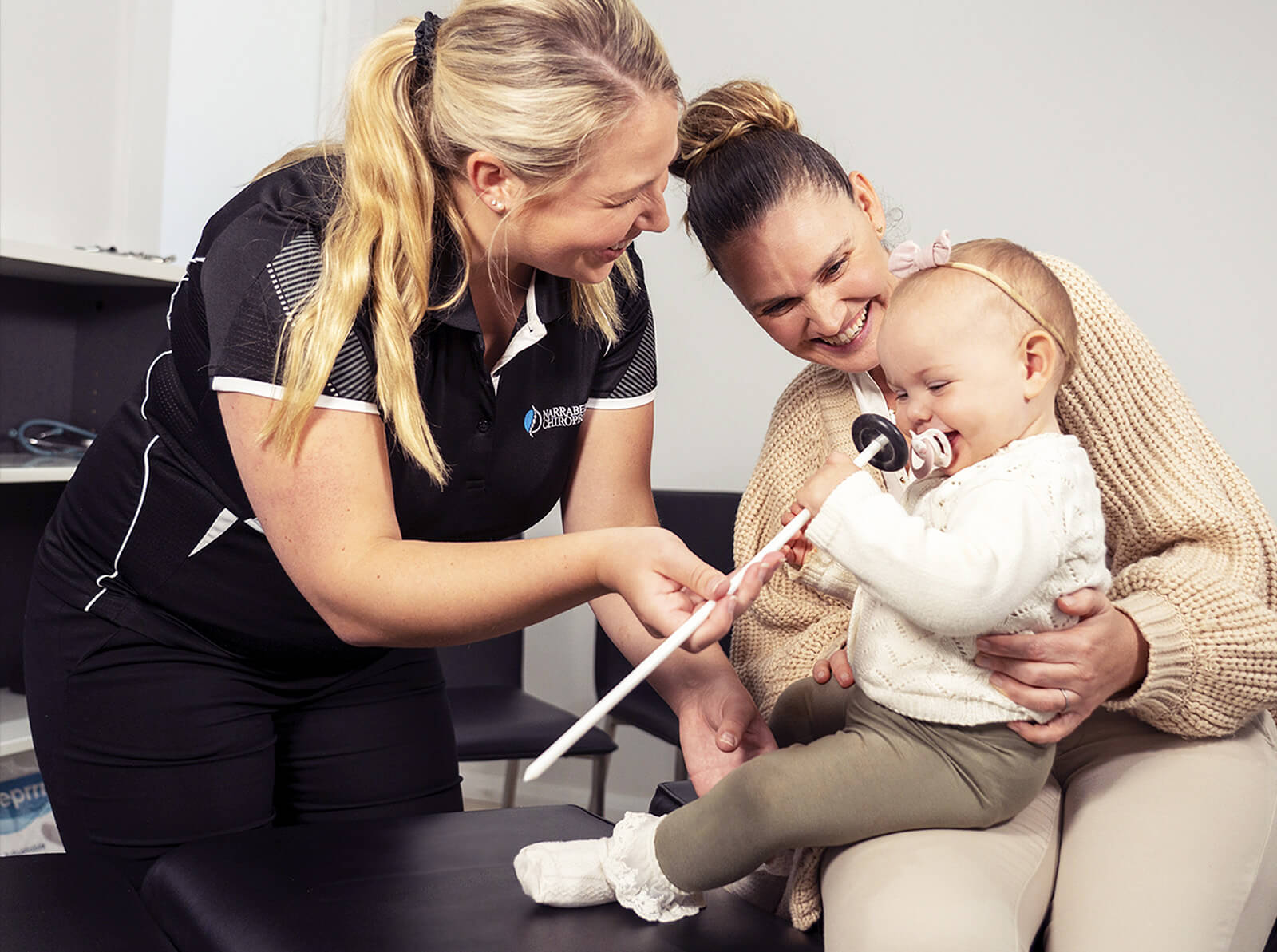 chiropractor smiling with mom and baby