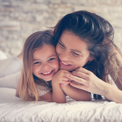 mom and child smiling on bed