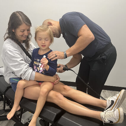 Dr. Stephen adjusting girl on mom's lap