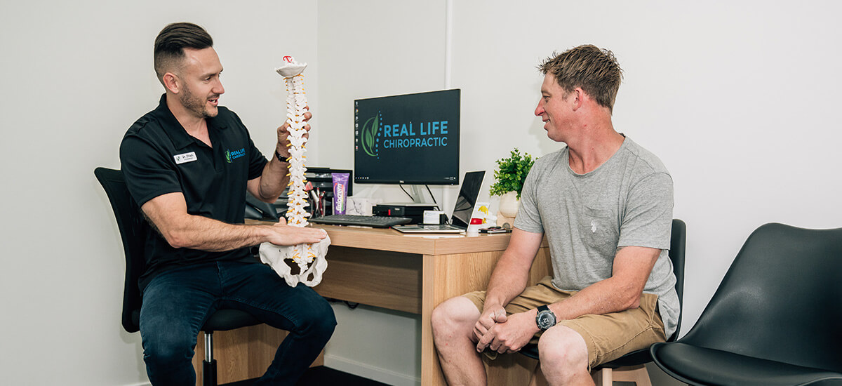 chiropractor showing patient spine model