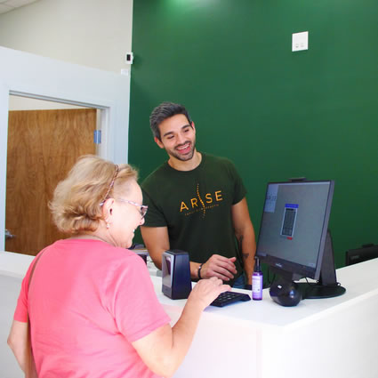 Patient and chiropractic assistant smiling at the front desk