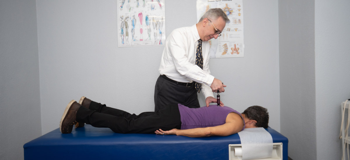 Dr. javaheri adjusting a patient's back with a chiropractic tool