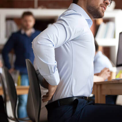 man in button up shirt at desk lower back pain