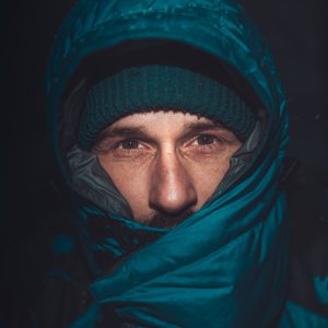 A man warmly dressed in a bubble jacket braves the cold with a determined expression.
