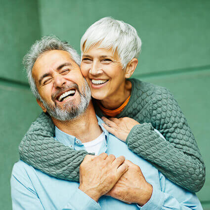 smiling elderly couple hug