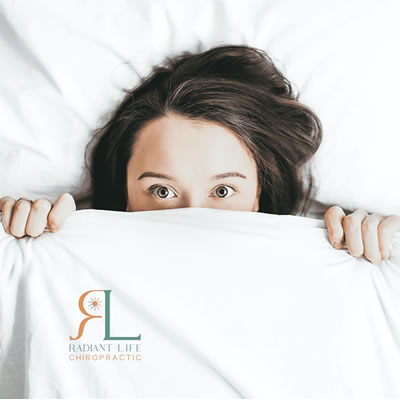 woman on bed covering face with blanket