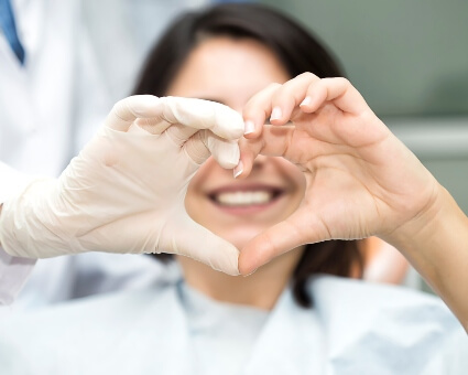 Dentist and patient making heart shape with hands