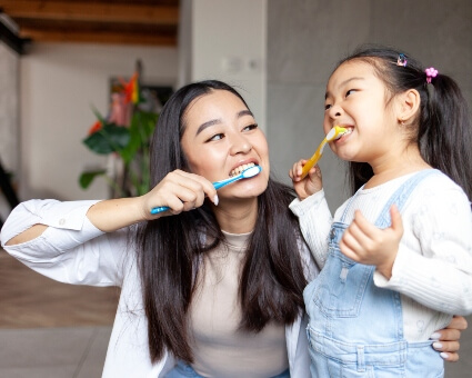 Mom and young daughter brushing their teeth