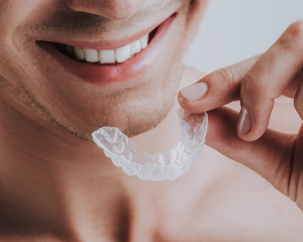 Smiling man holding a mouthguard