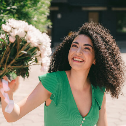 person with beautiful smile taking a bunch of flowers