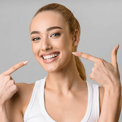 woman happily pointing to her white teeth
