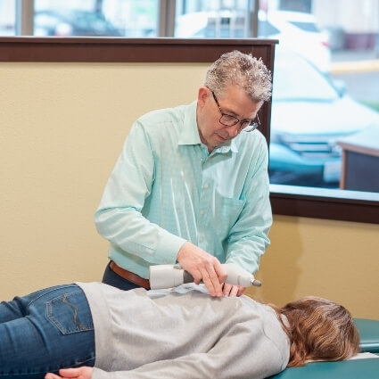 Dr Ludwig using activator tool on patients back
