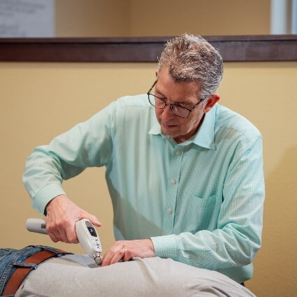 Dr Ludwig using activator tool on patients back