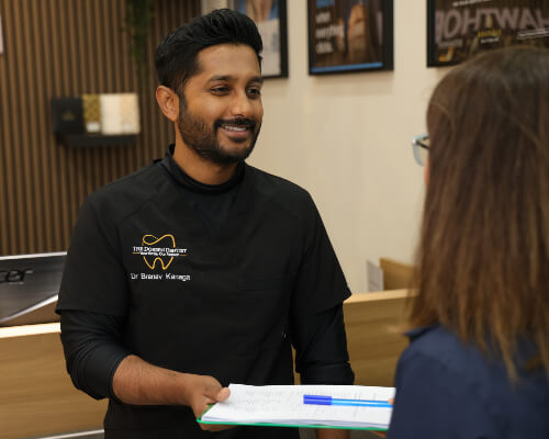 Dr. Branav smiling while holding paperwork