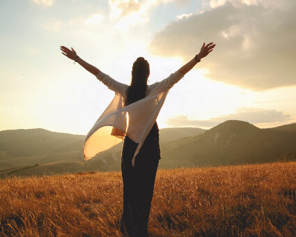 Woman out in nature with raised arms