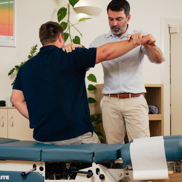 Male chiropractor stretching a patient's arm