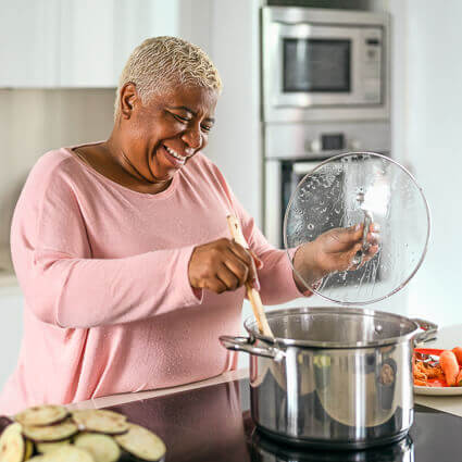 smiling-woman-lifting-lid-off-pot-of-food-sq