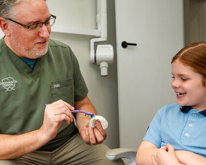 Dr Joshua brushing teeth model by child