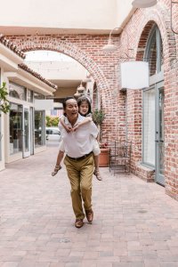 Senior carrying young girl in an outdoor alley, showcasing a joyful and loving family moment.