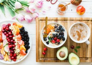 A bowl of yogurt with fruit and a cup of coffee for breakfast