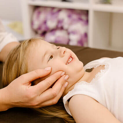 little girl smiling while chiropractor adjusts jaw