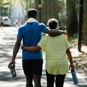 Two friends walking in a scenic park, enjoying a relaxing stroll on a sunny day.