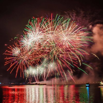 Colorful fireworks illuminating the night sky above a serene water body, creating a festive atmosphere.