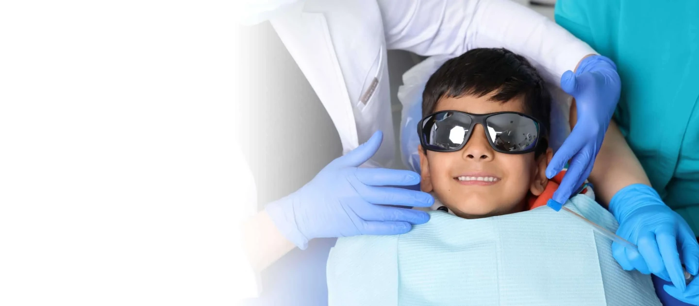 smiling boy with sunglasses getting a dental exam