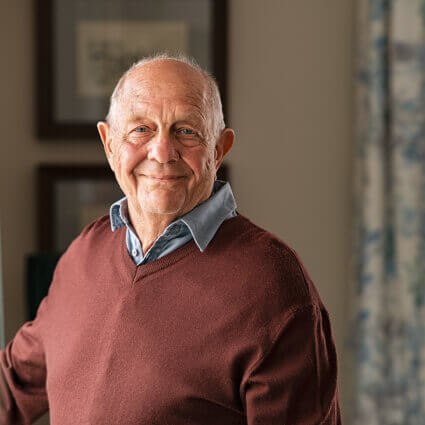 elderly man smiling wearing a sweater