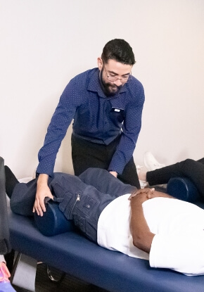 Chiropractor adjusting a male patient wearing a white shirt