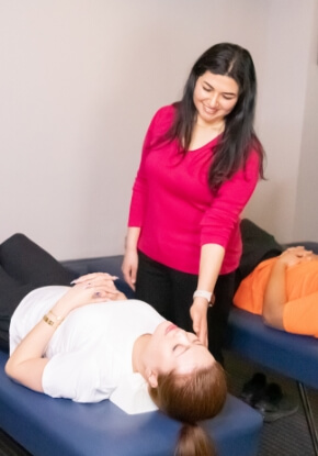 Chiropractor adjusting a female patient wearing a white shirt