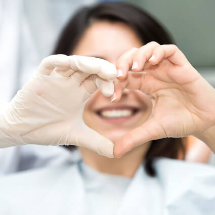 Dentist and patient making heart with hands