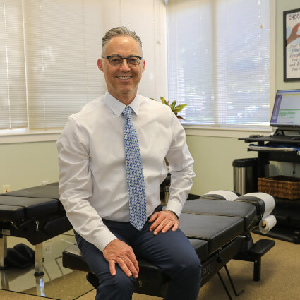 Dr. Ramzi sitting on adjustment table