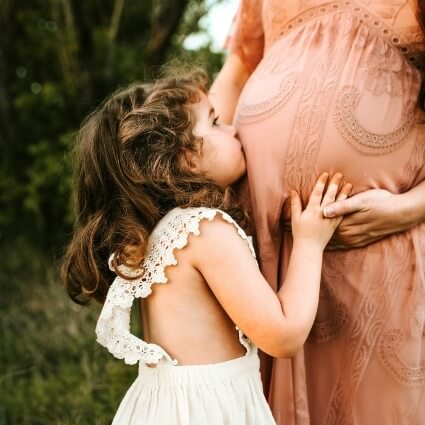 smiling kid kissing moms stomach